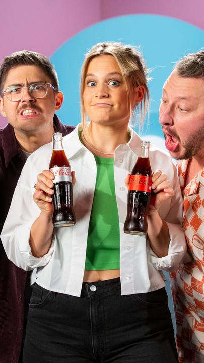 Lilly Temme, Flo Reza und Sebastian Lege posieren im Studio mit einer Flasche Coca Cola und einer Flasche Coke Zero.