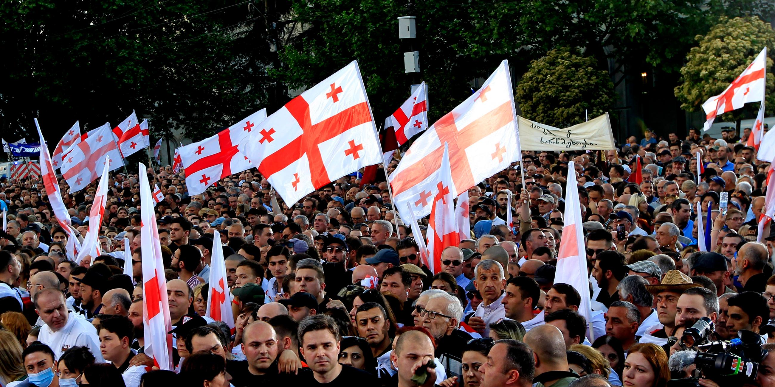 29.04.2024, Georgien, Tiflis: Regierungsfreundliche Demonstranten mit georgischen Nationalflaggen nehmen an einer Kundgebung zur Unterstützung des "russischen Gesetzes" in Tiflis, Georgien, teil.