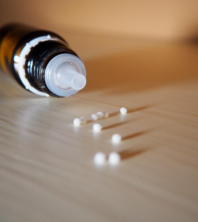 Homöopathie: Flasche und Kügelechen liegen auf einem Tisch