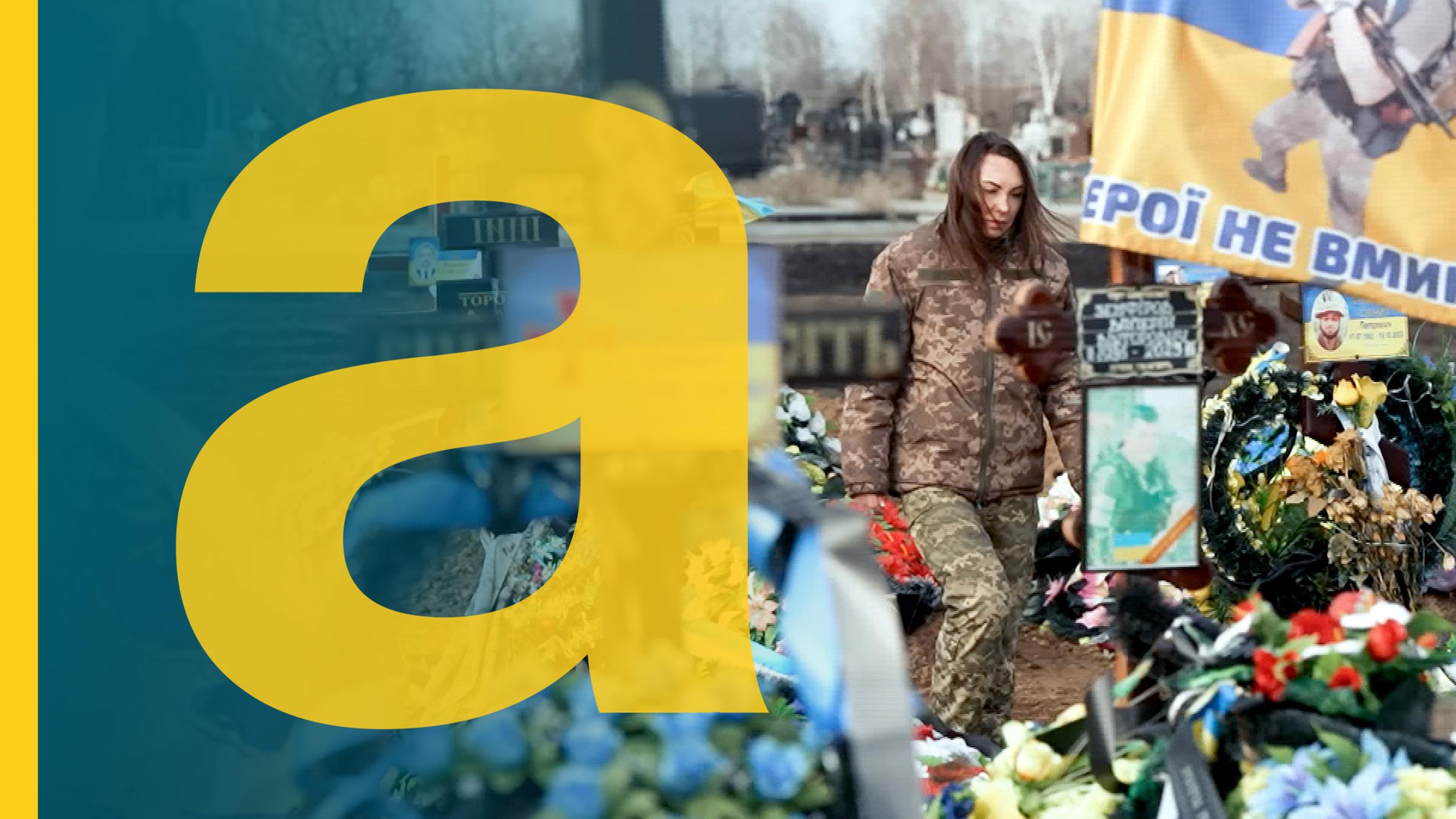 Auf dem Bild ist eine Soldatin auf einem ukrainischen Friedhof zu sehen.