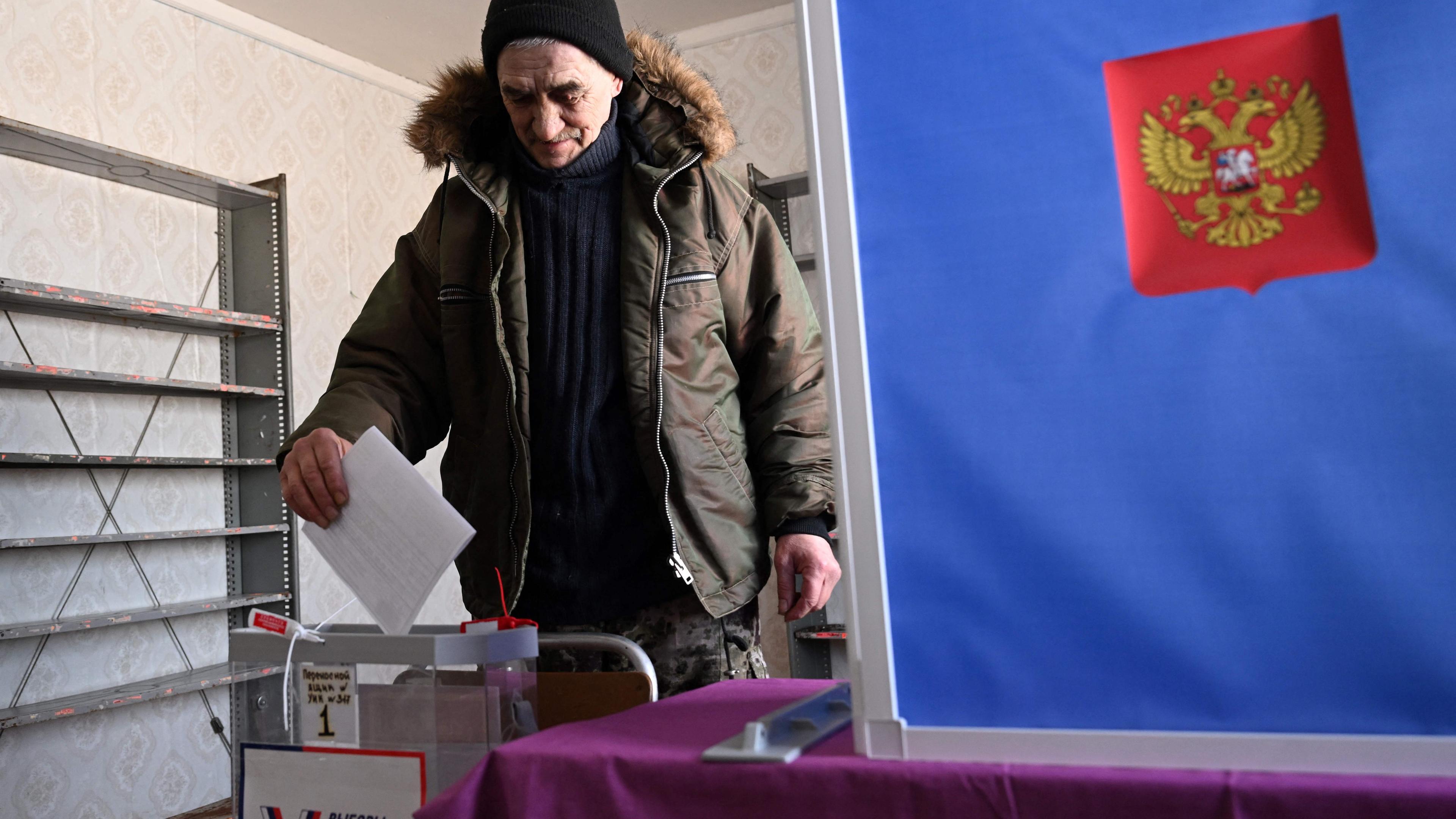 Ein Russe steckt den Wahlzettel in die Wahlurne