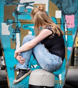 Jugendliche sitzt vor einer Wand