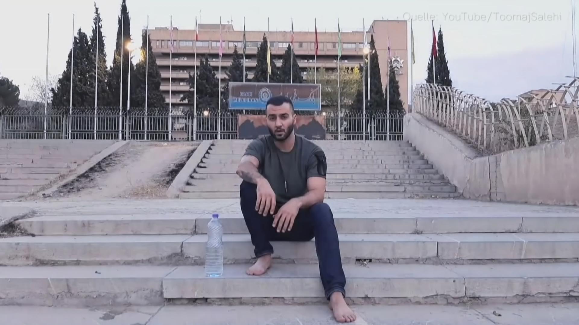 Der iranische Rapper Salehi sitzt auf einer Treppe vor einem Gebäude