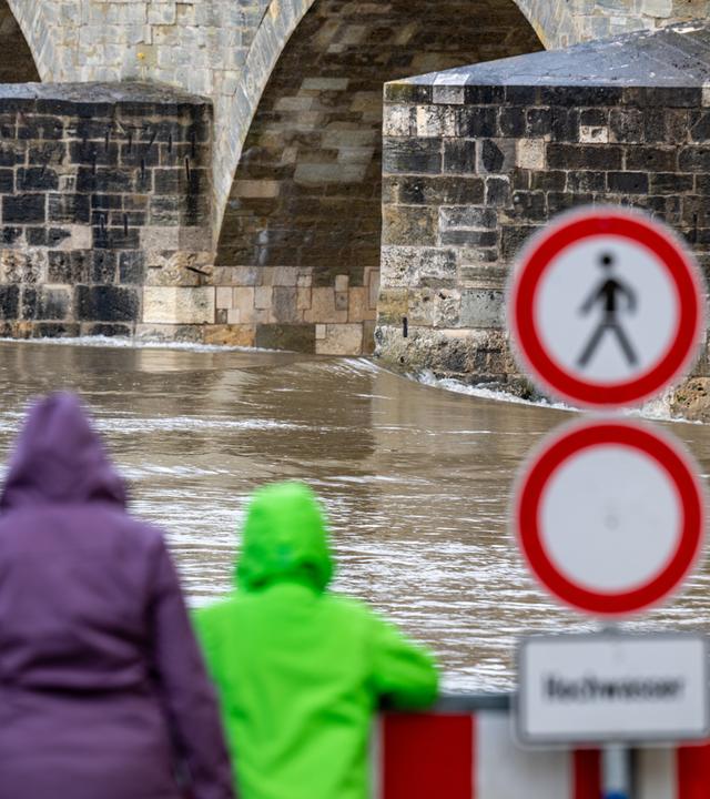 Hochwasser: Zwei Menschen schauen im Regen auf den Fluss