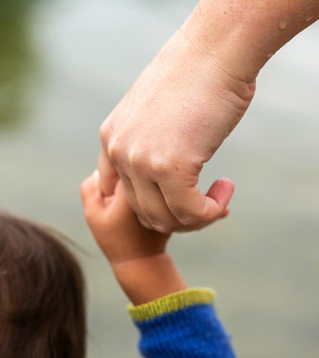 Frau hält Kind an der Hand