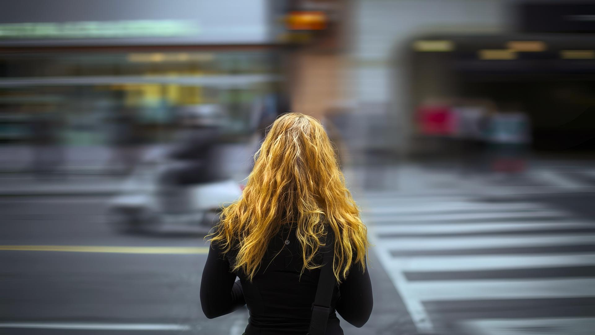 Junge Fau von hinten - steht an einer Straße