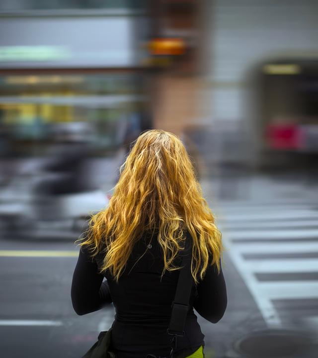 Junge Fau von hinten - steht an einer Straße