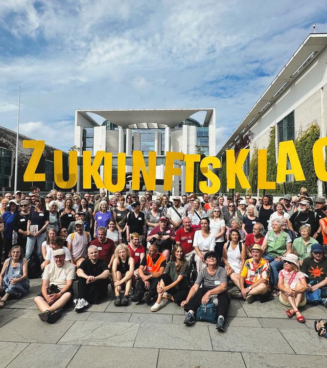 Menschen mit Schildern mit der Aufschrift ZUkunftsklage