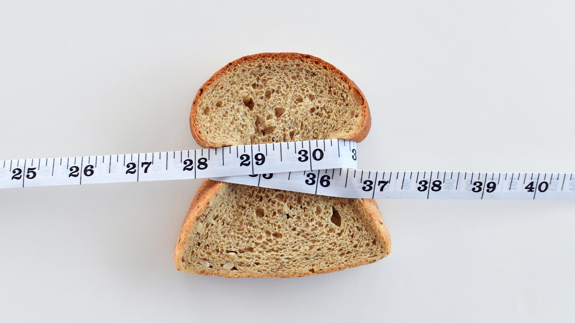 Eine Scheibe Brot, die mit einem Maßband umwickelt ist.