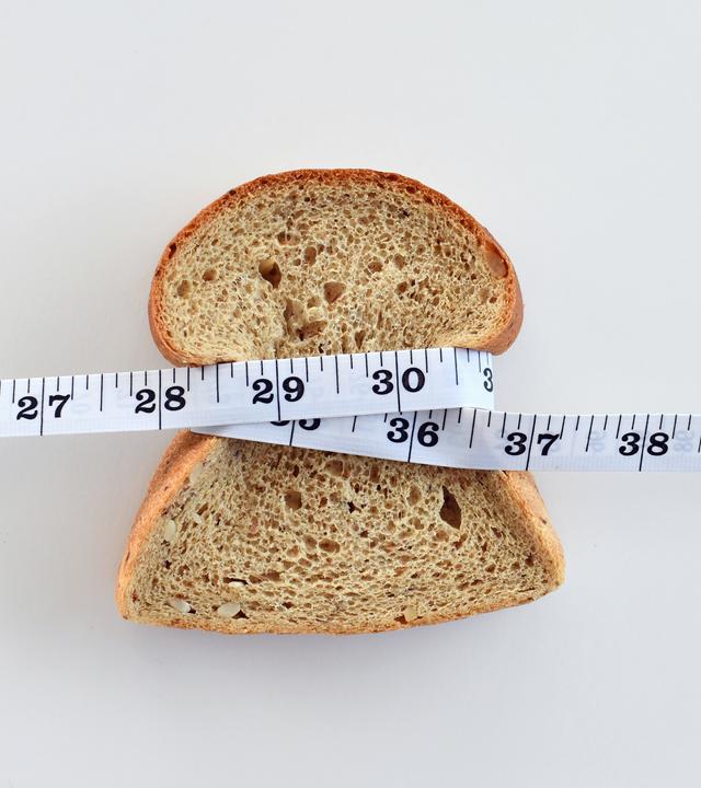 Eine Scheibe Brot, die mit einem Maßband umwickelt ist.