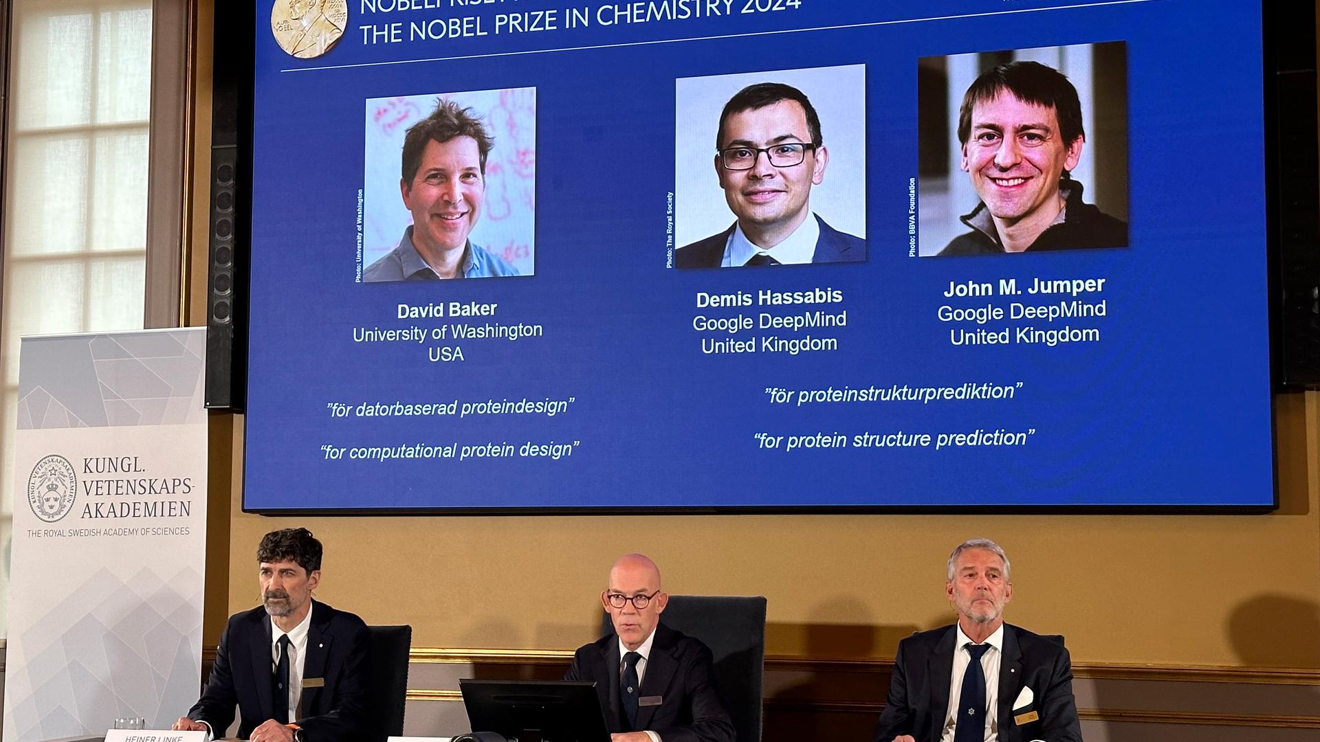 Bekanntgabe Nobelpreis 2024 für Chemie - Gremium vor Videoleinwand mit Preisträgern David Baker, Demis Hassabis und John M. Jumper