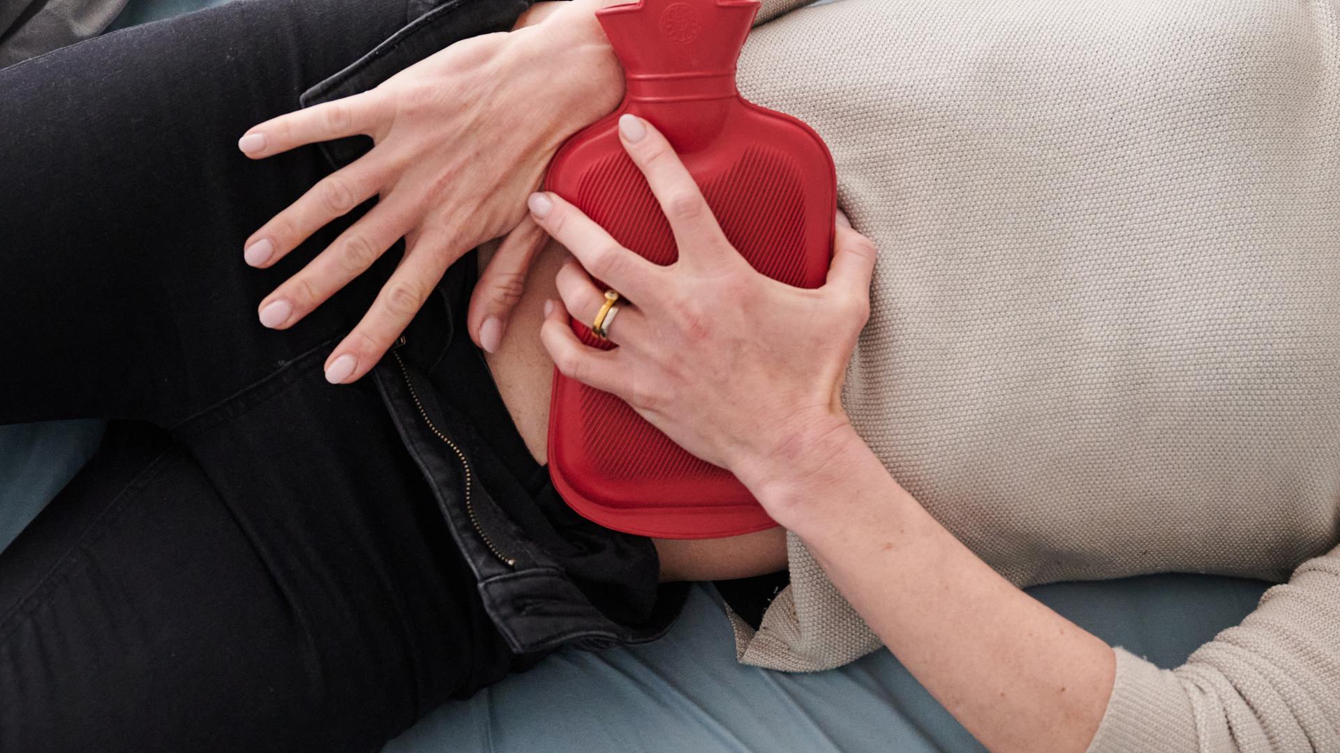 Frau hält sich eine Wämflasche auf den Bauch