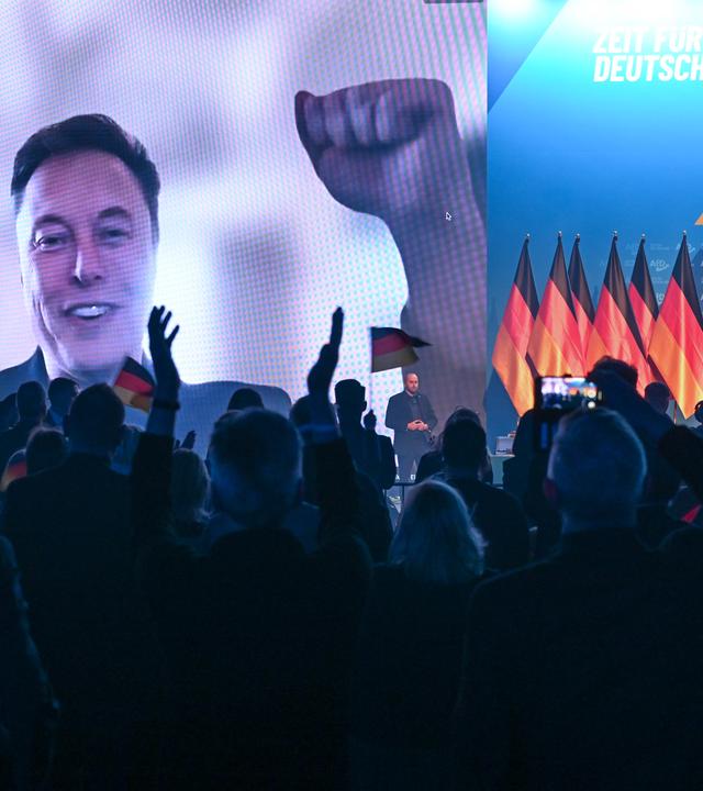 Über eine Videoeinblendung unterhält sich US-Miliardär Elon Musk mit Alice Weidel (r), Bundesvorsitzende der AfD, beim Wahlkampfauftakt der AfD.