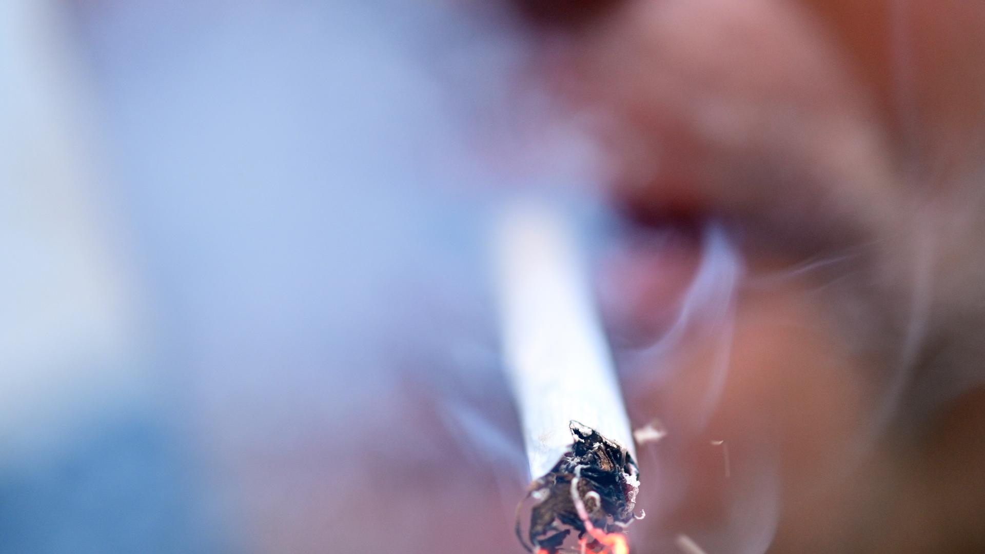 Person raucht eine glühende Zigarette