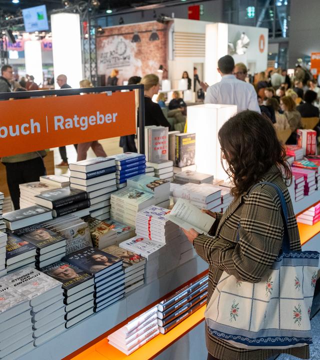 Eine Besucherin schaut sich an einem Verlagsstand Bücher an. Die 77. Frankfurter Buchmesse findet vom 15. bis 19. Oktober 2025 statt. Ehrengast sind die Philippinen.