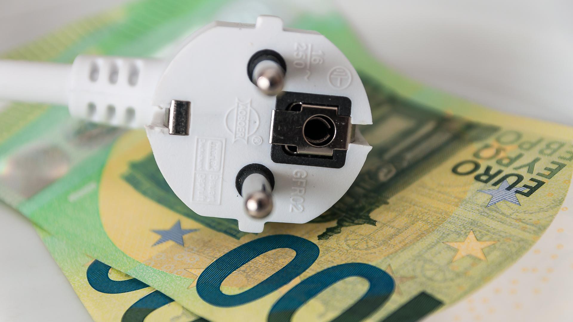 Ein Haushalts-Stromkabel liegt auf Geldscheinen