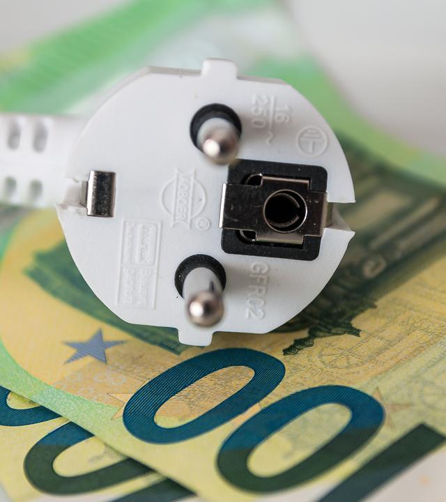 Ein Haushalts-Stromkabel liegt auf Geldscheinen