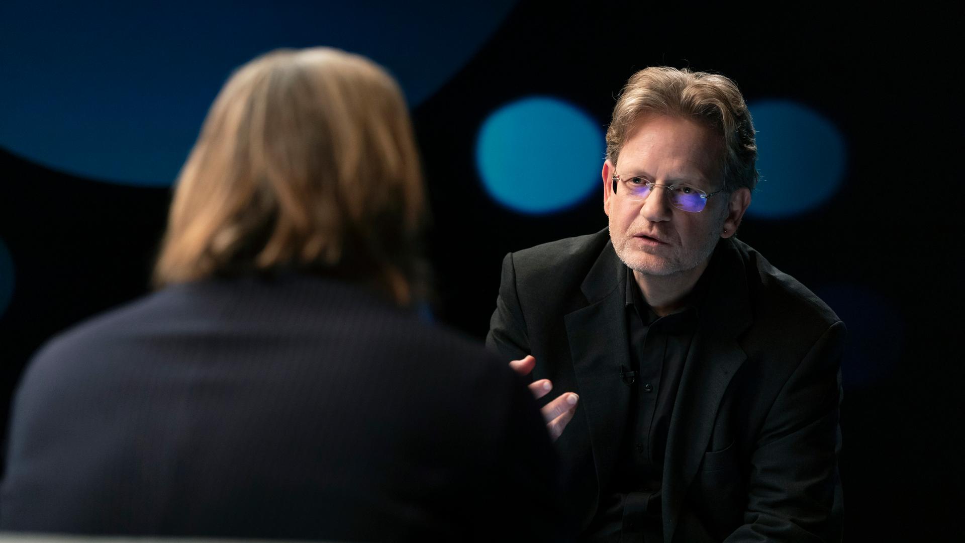 Richard David Precht diskutiert mit dem Rechtsexperten Kai Ambos. Beide sitzen sich im Studio gegenüber.