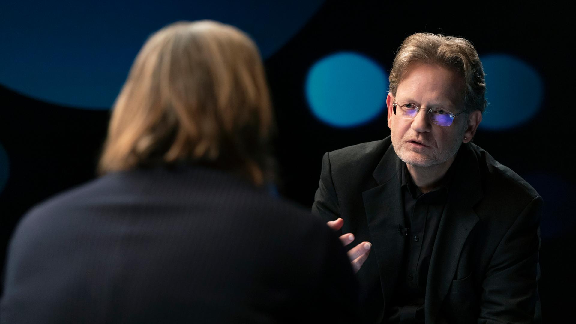Richard David Precht diskutiert mit dem Rechtsexperten Kai Ambos. Beide sitzen sich im Studio gegenüber.