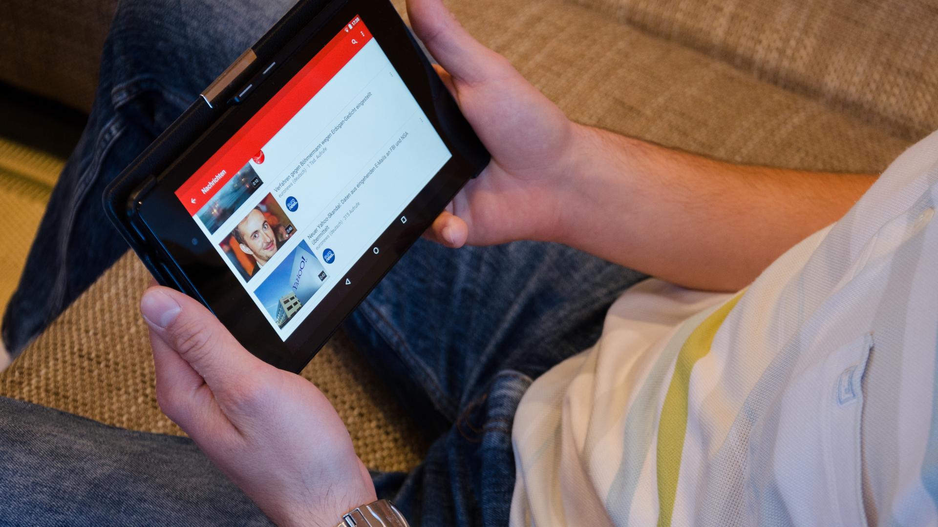 Mann auf dem Sofa schaut Video auf einem Tablet