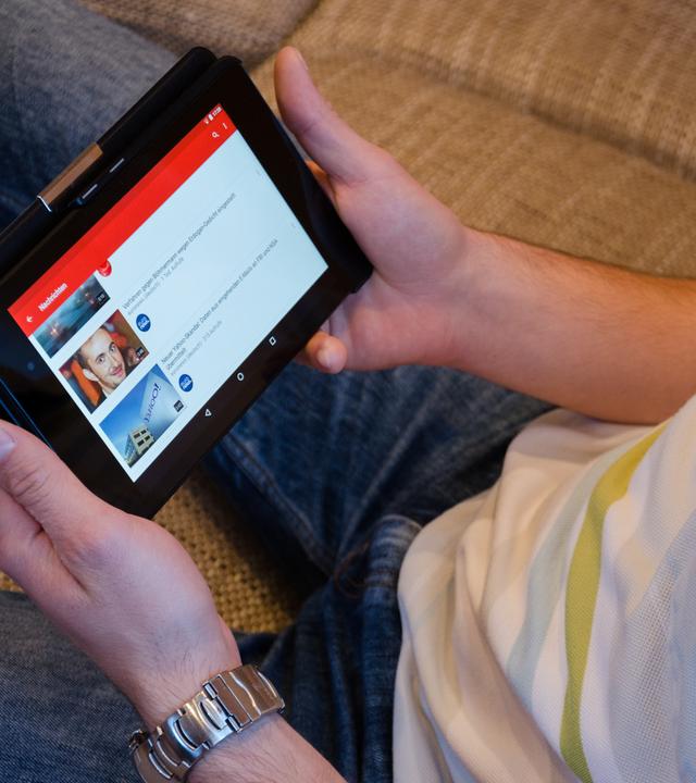 Mann auf dem Sofa schaut Video auf einem Tablet