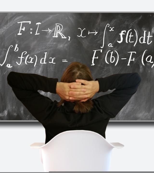 Verzweifelter Schüler sizt vor einer Tafel mit Matheformeln
