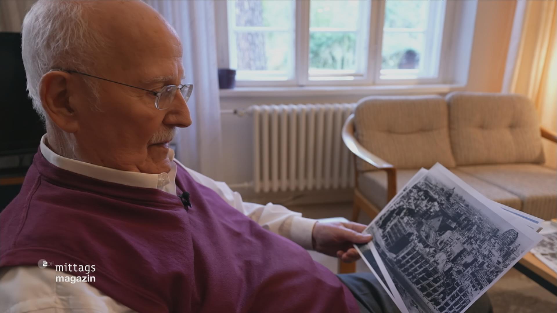Weltkriegszeitzeuge Günter Böhm schaut auf Photos des zerstörten Berlin