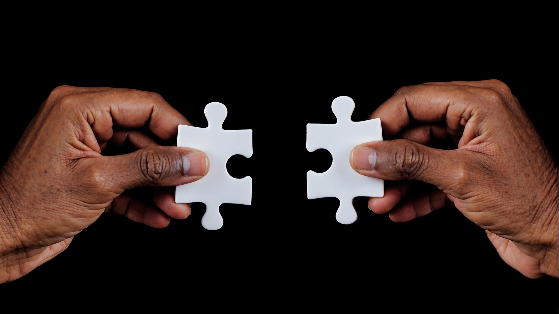 Zwei Hände, die Puzzleteile halten
