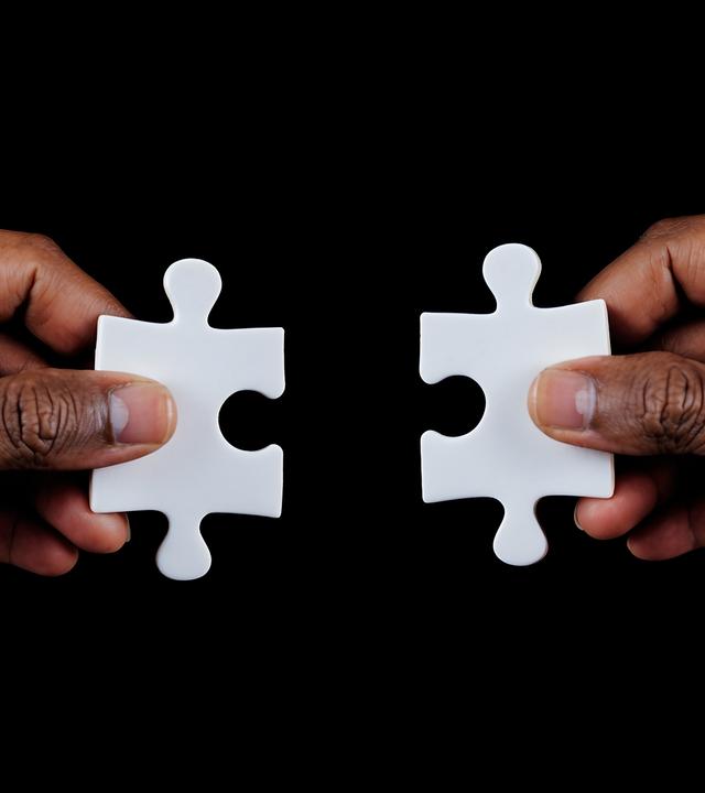 Zwei Hände, die Puzzleteile halten