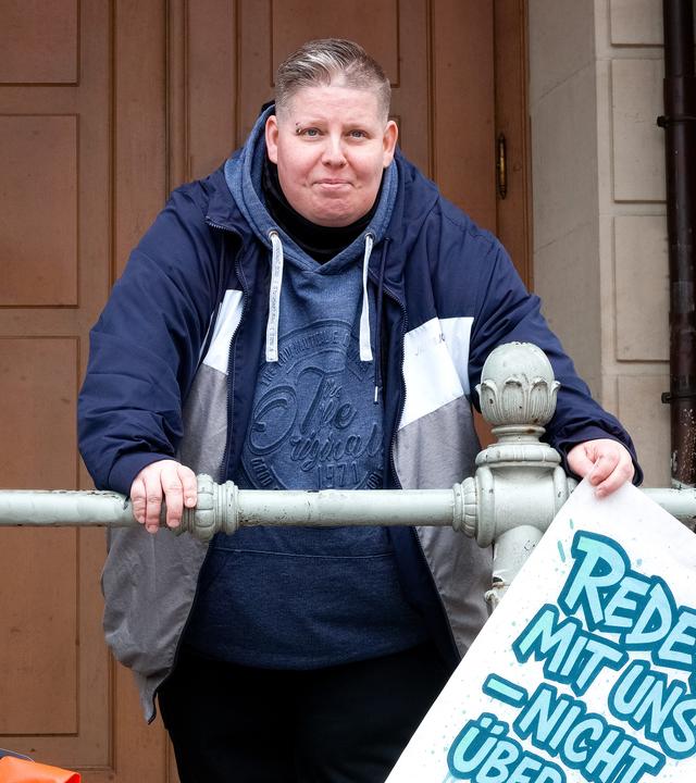 Nancy Frind hält Plakat mit der Aufschrift „Redet mit uns – nicht über uns.“
