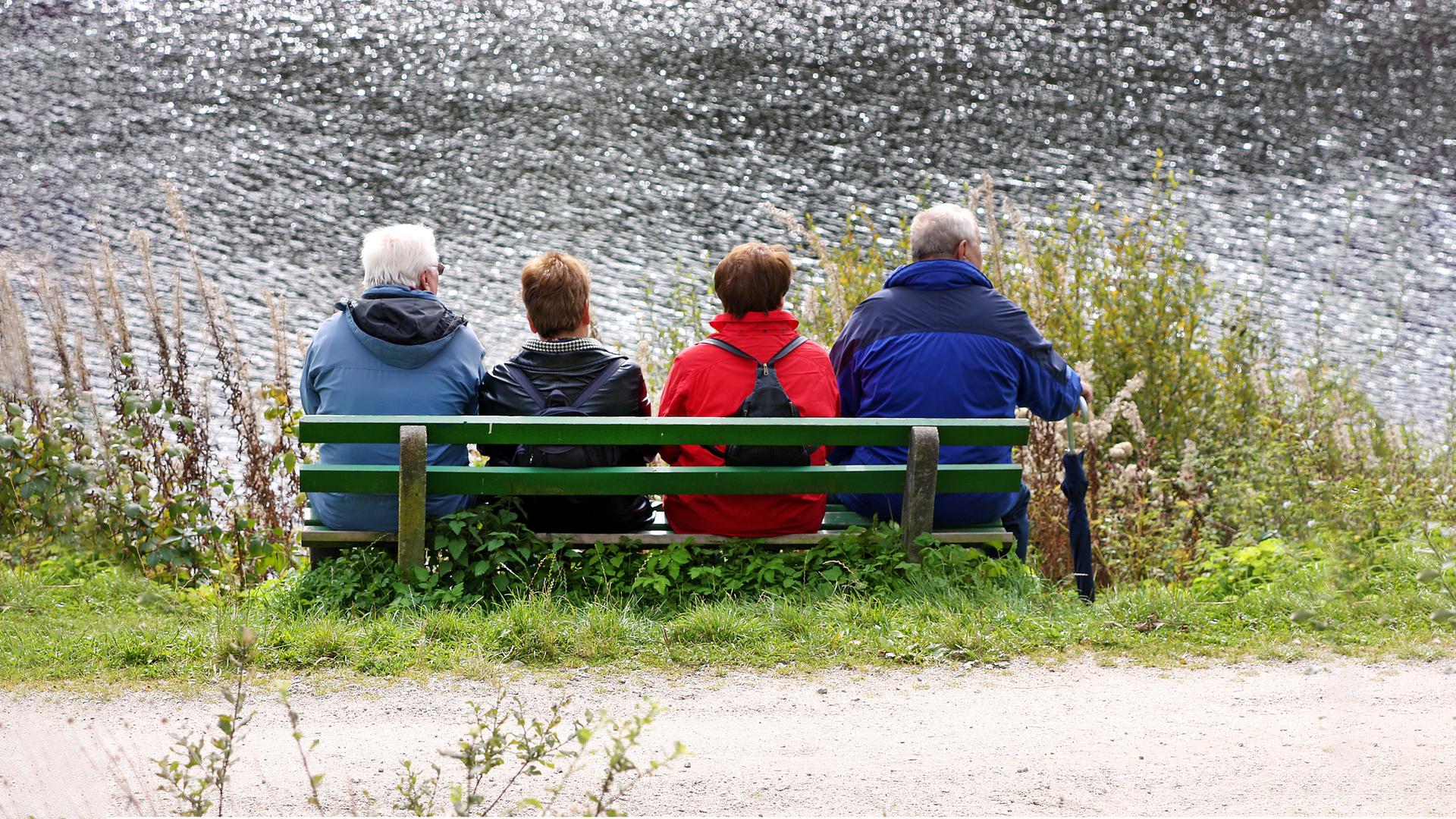 Ältere Menschen auf einer Bank am Wasser