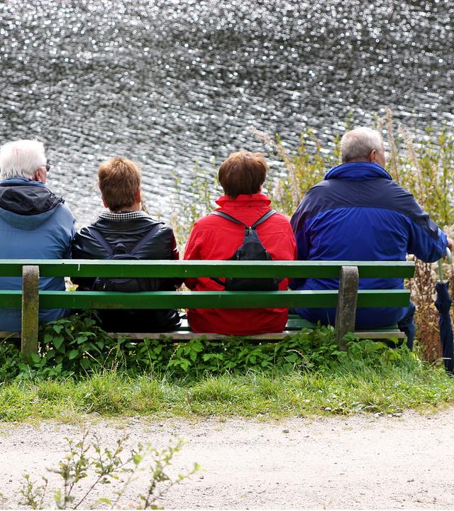 Ältere Menschen auf einer Bank am Wasser