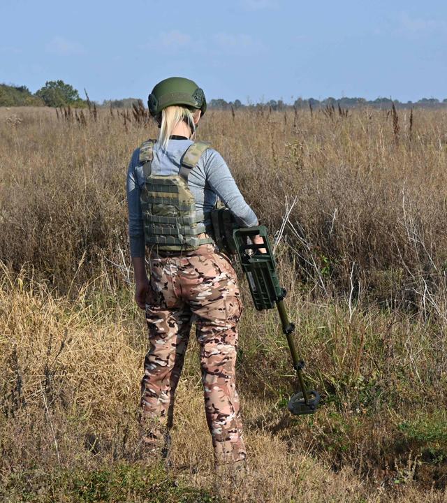 Eine Frau sucht mit einem Metalldetektor nach Minen im Boden - in der Ukraine keine Seltenheit. Immer mehr Frauen werden zu Minensucherinnen ausgebildet.