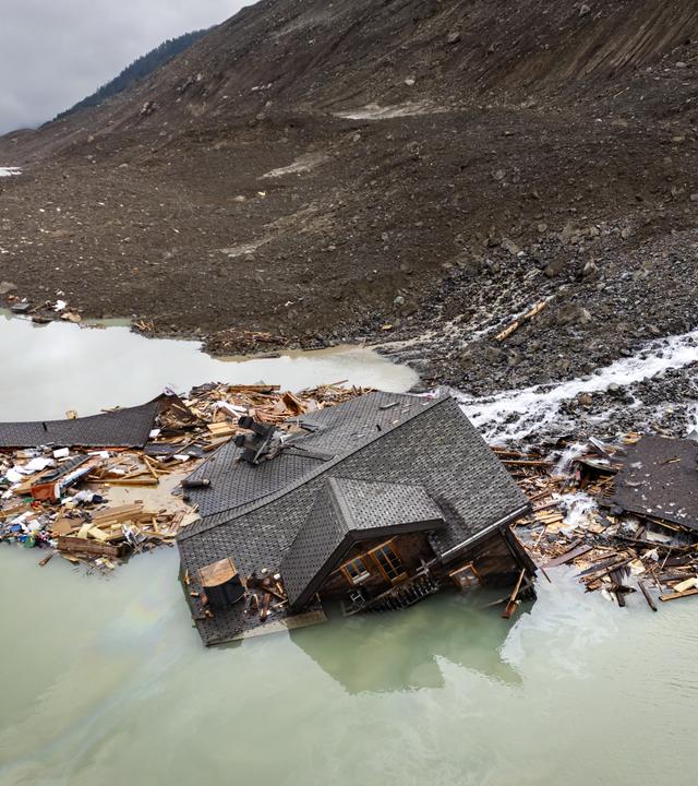 Ein teilweise verschüttetes Haus ragt aus Geröll und WasserTeilweise verschüttetes Haus ragt aus Geröll und Wasser – letzter sichtbarer Rest nach dem Gletschersturz in Blatten.