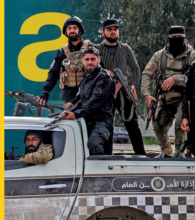 Sicherheitskräfte der syrischen Übergangsregierung stehen im Fond eines Fahrzeugs, das an einer Straße geparkt ist