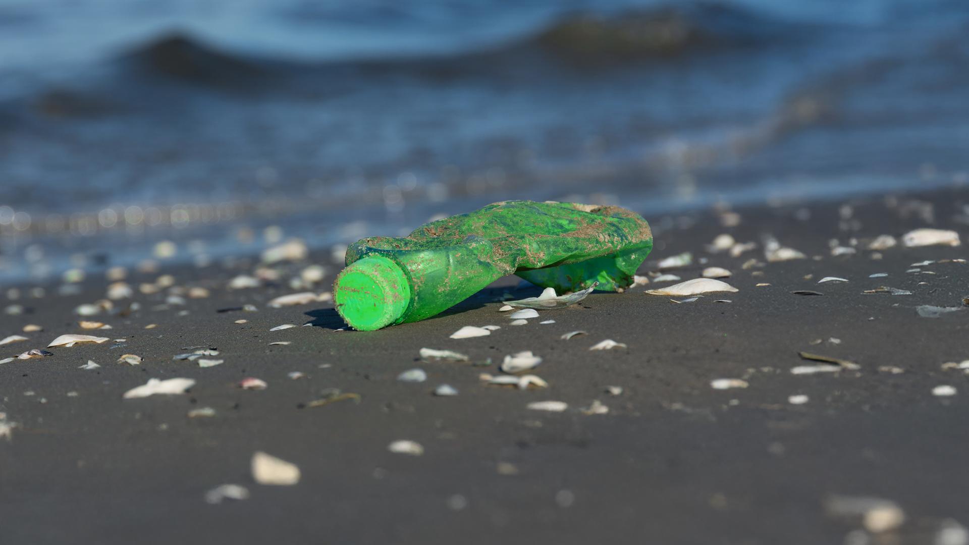 Eine weggeworfene Plastikflasche liegt im Sand – Symbol für die Umweltverschmutzung und das Scheitern internationaler Verhandlungen beim Plastikgipfel.