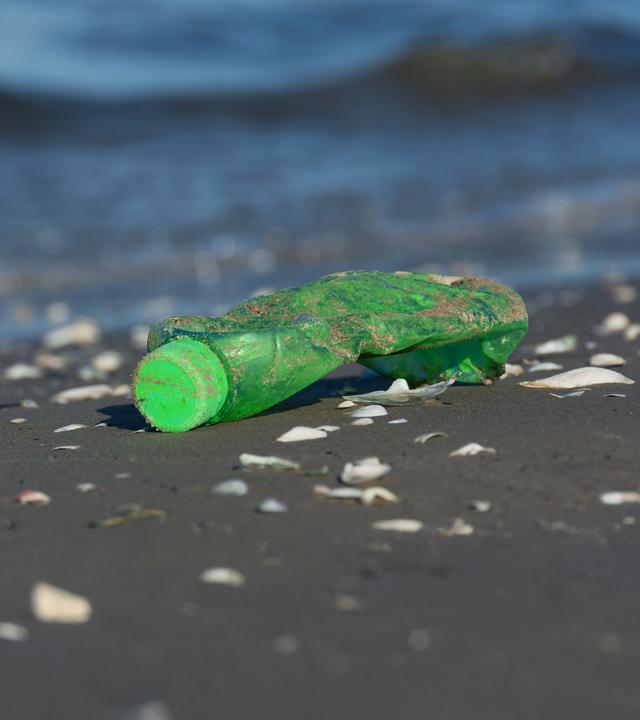 Eine weggeworfene Plastikflasche liegt im Sand – Symbol für die Umweltverschmutzung und das Scheitern internationaler Verhandlungen beim Plastikgipfel.