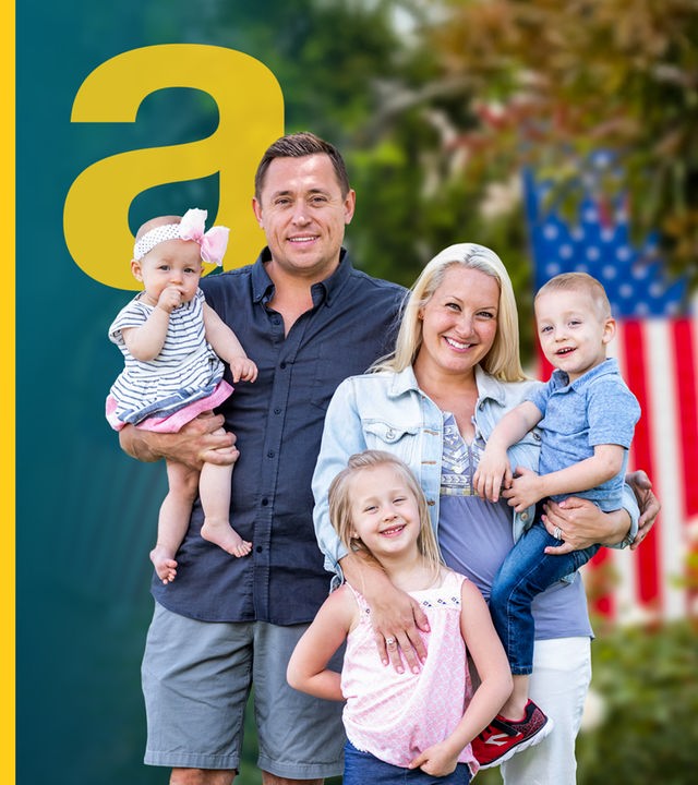 Glückliche junge kaukasische Familie vor Häusern mit amerikanischen Flaggen