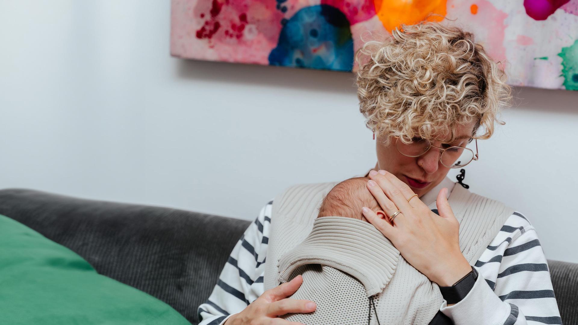 "37°Leben: Das Wochenbett - Glückshormone und Albträume": Jacqui trägt ihren Sohn Sohn Jonah im Tragetuch vor sich und schaut ihn an.