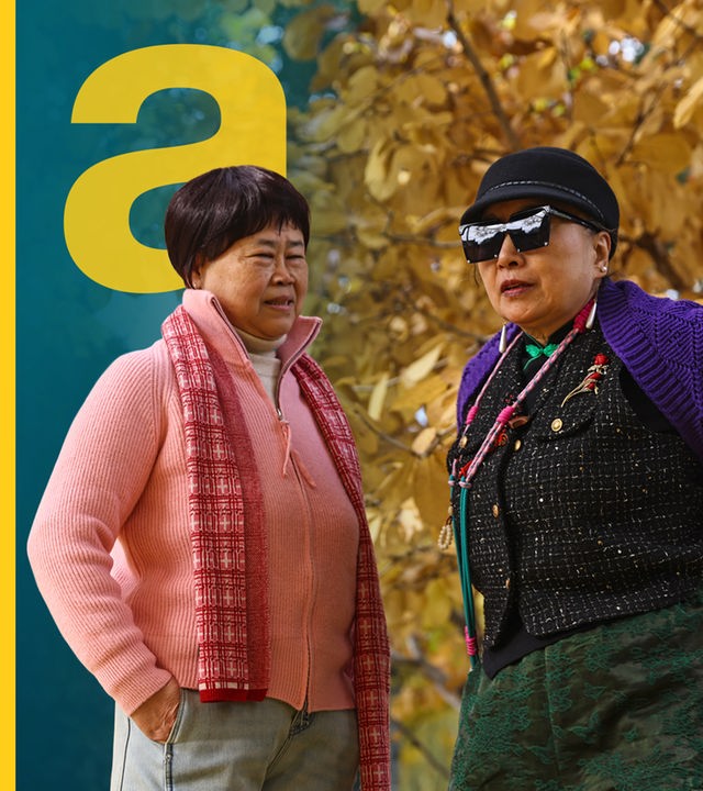 Zwei etwas ältere Menschen stehen an einem Herbsttag in einem öffentlichen Park in Peking, China, am 10. November 2025. Eine Frau mit pinkem Outfit, eine andere Person mit einer lila Jacke und einer schwarzen Sonnenbrille.
