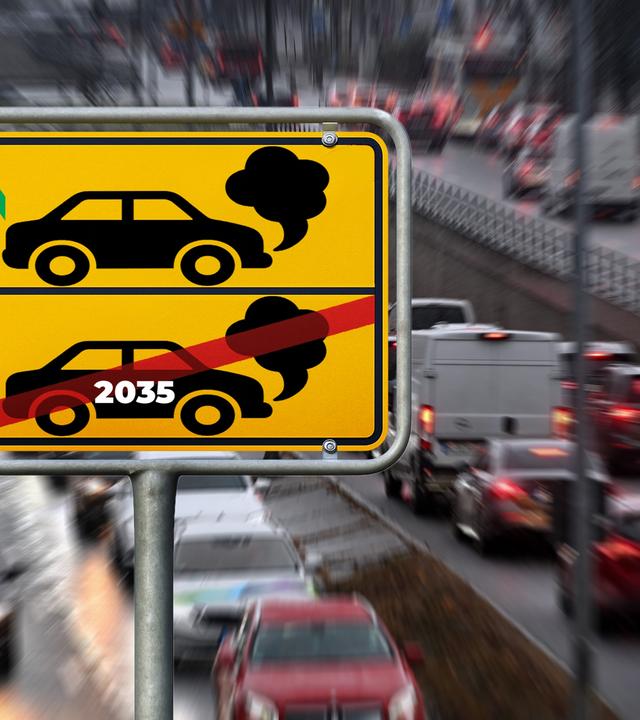 Kein Verbrenner-Stopp ab 2030: Das hat der Bundesgerichtshof entschieden. BMW und Mercedes-Benz dürfen auch nach 2030 Verbrenner verkaufen. (Im Bild: Im Hintergrund eine Autoschlange, davor ein gelbes Schild mit Aufschrift)