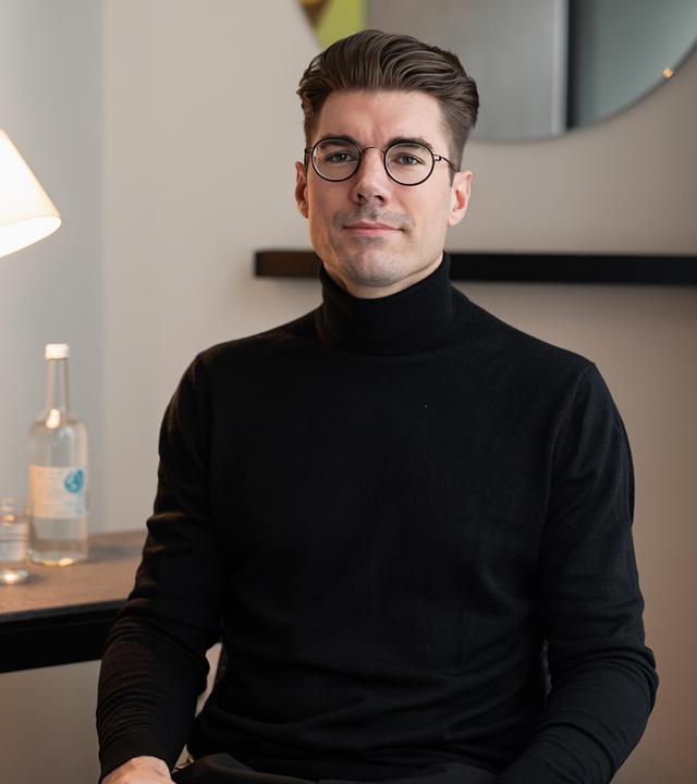 Patient Paul Gressenberger sitzt mit geschlossenen Augen auf einem Behandlungsstuhl. Professor Riedel sitzt vor ihm und schaut sich seine Nase an.