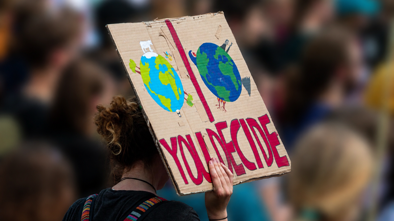Auf der Bonner UN-Klimazwischenkonferenz zur COP31 erhöhen junge Menschen den Druck auf Deligierte und Konferenzteilnehmer. (Auf dem Bild ist eine Frau von hinten zu sehen, die ein Schild mit Aufschrift hochhält)