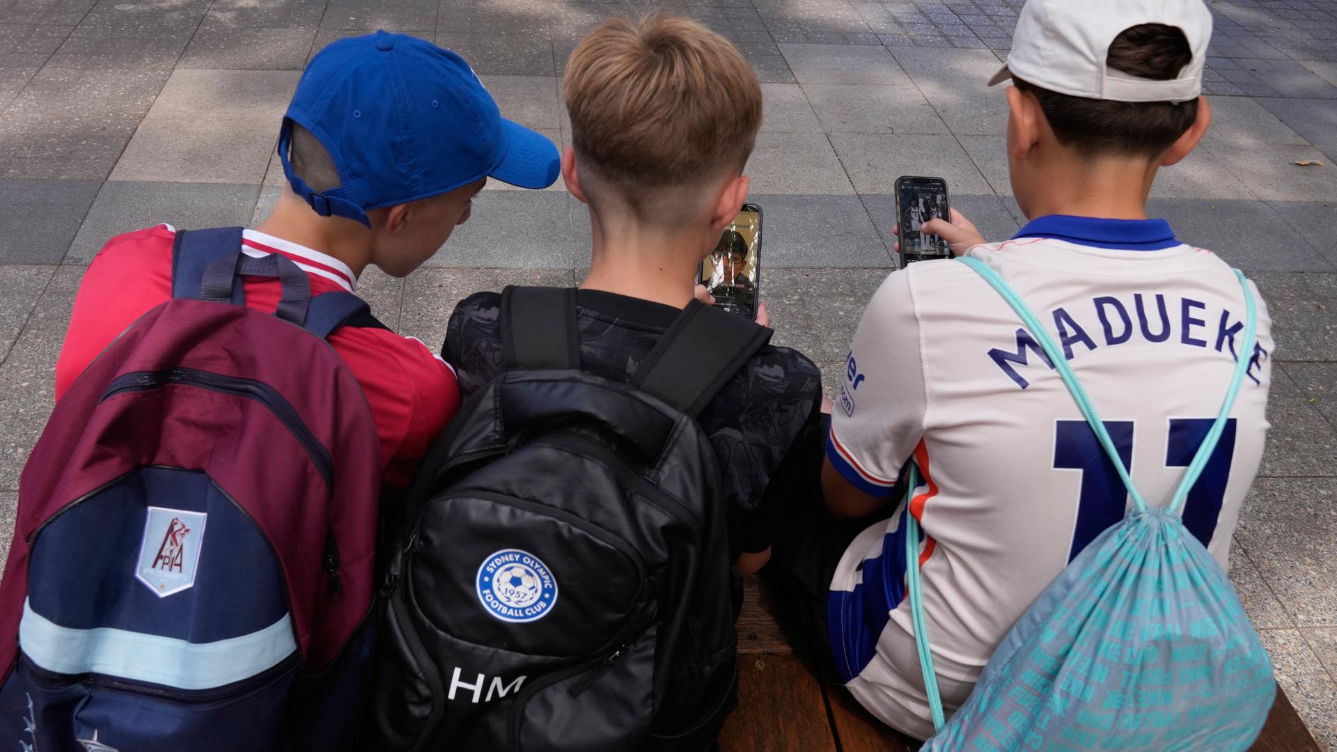 ikTok, Insta, Snapchat: Während andere Länder Verbote planen, setzt Deutschlands Expertenkommission auf Altersgrenzen, Risiko-Bewertungen und Schulungen. (Bild:Drei Kinder, sitzend, zu sehen von hinten, schauen auf ein Handy)