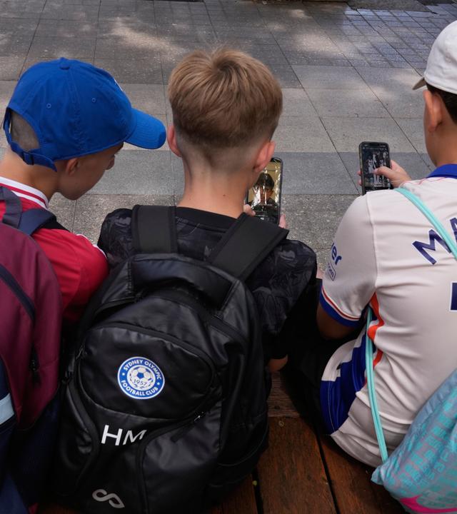ikTok, Insta, Snapchat: Während andere Länder Verbote planen, setzt Deutschlands Expertenkommission auf Altersgrenzen, Risiko-Bewertungen und Schulungen. (Bild:Drei Kinder, sitzend, zu sehen von hinten, schauen auf ein Handy)