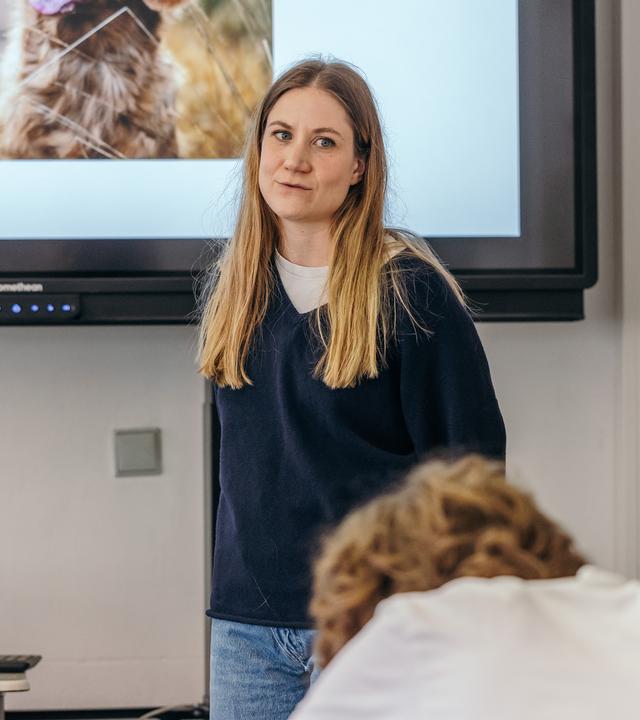 37°Leben: Life Teacher: Was nicht im Lehrplan steht": Charlotte steht vor einer Gruppe Schülern im Klassenraum. Auf dem Screen hinter ihr ist ein Hund abgebildet.