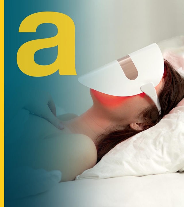 Eine Frau liegt im Bett und trägt dabei eine Maske zur LED-Lichttherapie