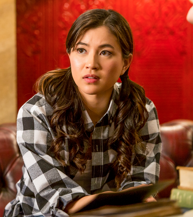 Kyra entwickelt einen Plan. Dabei sitzt sie fokussiert schauend auf einem Sofa.