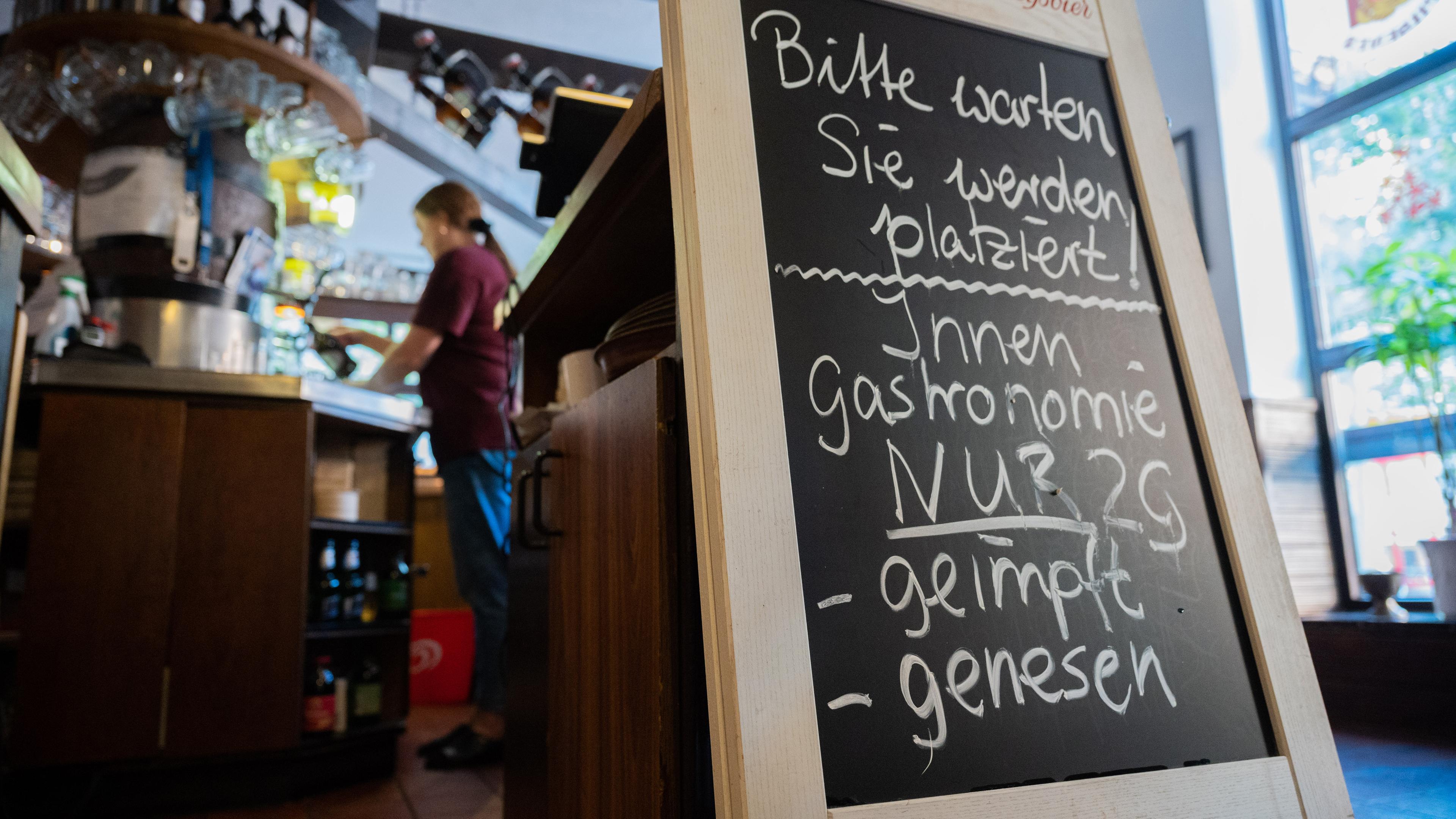 Eine Tafel mit der Aufschrift «Innengastronomie - Nur 2G - geimpft - genesen» steht in Schadt_s Brauerei Gasthaus.  Foto: Julian Stratenschulte/dpa +++ dpa-Bildfunk +++ *