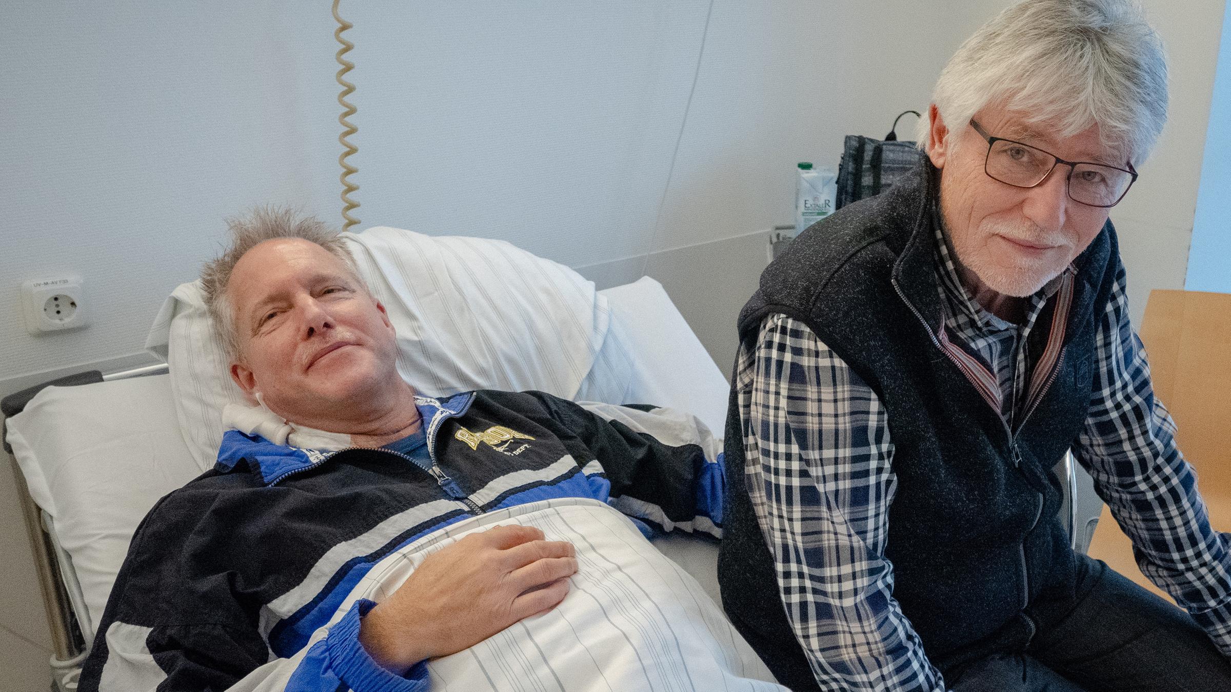 Joachim sitzt am Krankenhaus-Bett seines Freundes Manfred